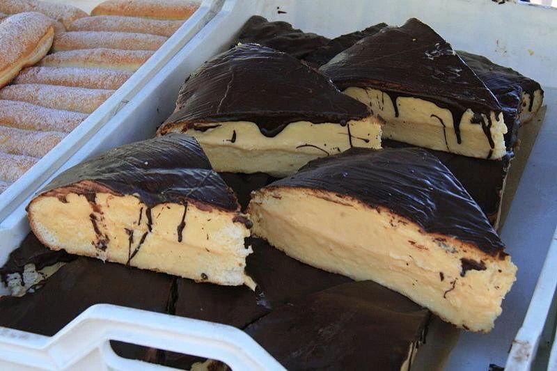 Bandeja con porciones triangulares de pastel de crema cubierto de chocolate.