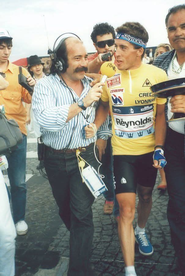 Periodista con auriculares entrevistando a un ciclista con maillot amarillo