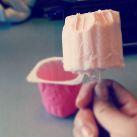 Petit Suisse congelado sacado de su tarrina pinchado en un palillo.