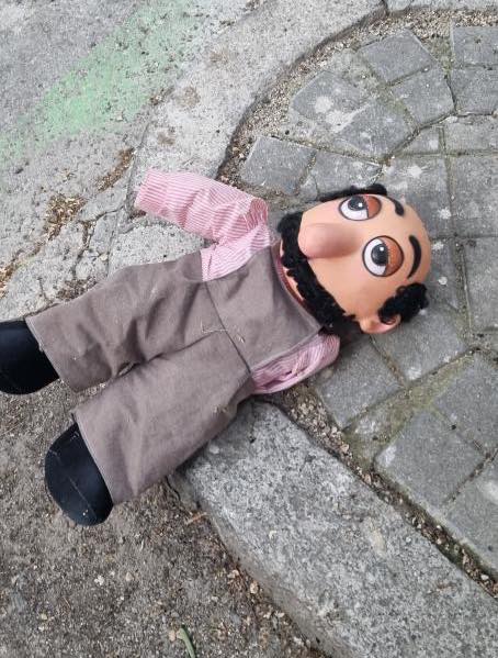 Muñeco con traje y bigote tirado en el suelo