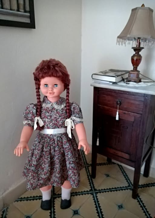 Muñeca grande con trenzas pelirrojas y vestido de flores.