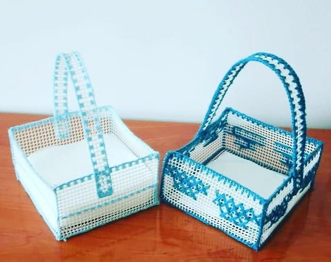 Dos servilleteros de rejilla de plástico bordados en azul.