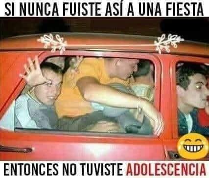 Grupo de chavales apretujados dentro de un coche rojo, saludando por la ventanilla.