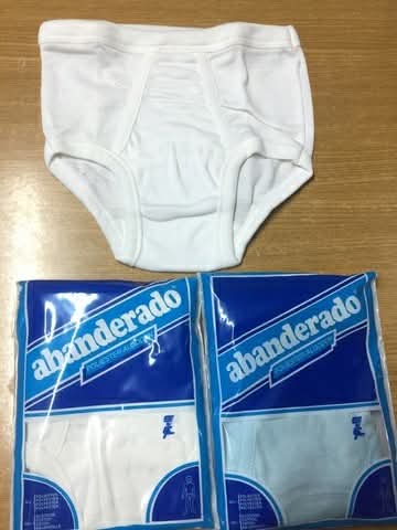 Slip blanco de niño junto a dos paquetes de Abanderado.
