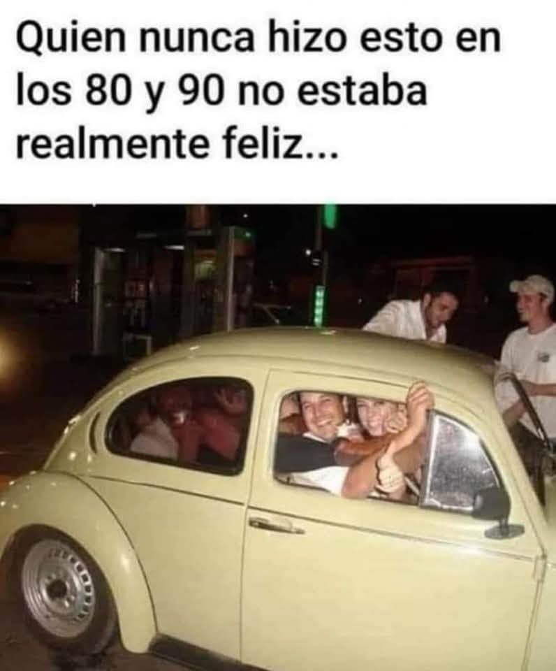 Volkswagen Escarabajo de color crema lleno de gente sonriendo por las ventanillas mientras otros intentan subir.