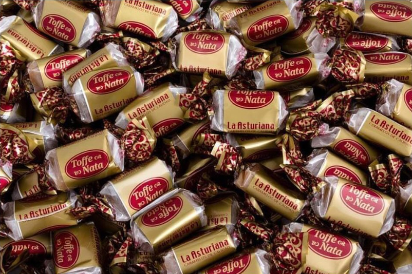 Montón de caramelos Toffe de nata La Asturiana con envoltorio dorado.