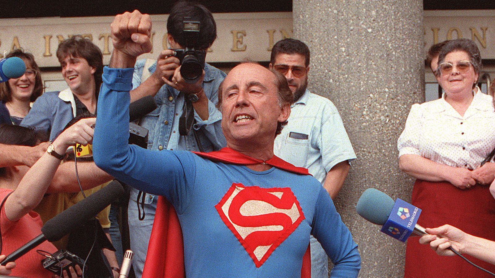 Hombre disfrazado de Superman rodeado de periodistas y curiosos