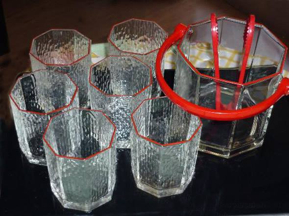Vasos de cristal octogonales con una cubitera con pinzas rojas.